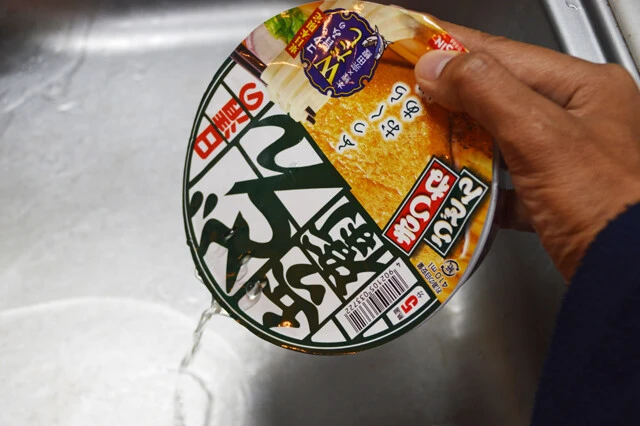 (3)湯切り! どん兵衛を粉末スープ抜きで作り、熱湯を注いで5分後に湯切りする。ざるを使用すれば手っ取り早いが、包丁でフタに穴を開ければカップ焼きそばのように湯切り可能だ