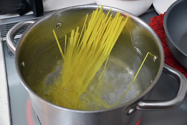 (1)ゆでる! 大きめの鍋にお湯を沸かしてパスタをゆで、ざるで水気をきる。パスタ100gにはシャカシャカポテト シーズニングが2袋ほど必要。大盛りにしたい場合は粉の量も調整しよう