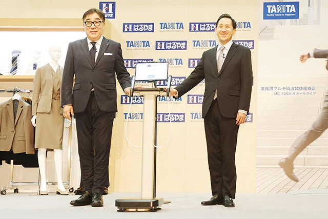 記者発表では、はるやま商事の中村宏明社長（左）とタニタの谷田千里社長（右）によるデモンストレーションが行なわれた