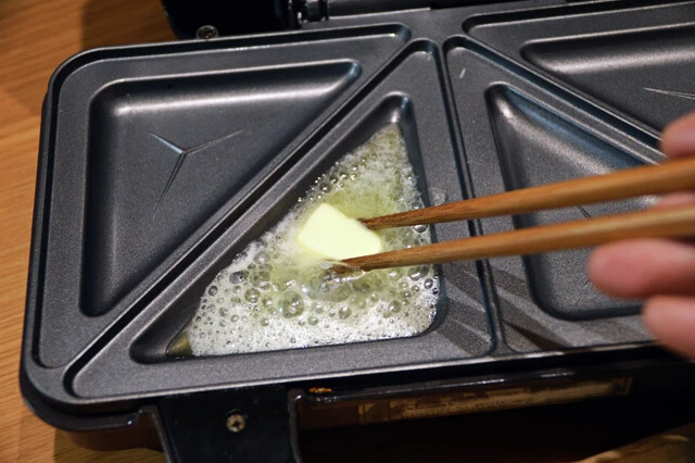 (2)バター! ホットサンドメーカーを温め始めたらバターを塗り、全体に広げていく。底面だけでなく上面にもバターをたっぷりと塗っておこう。この手順はなるべく手早く済ませよう