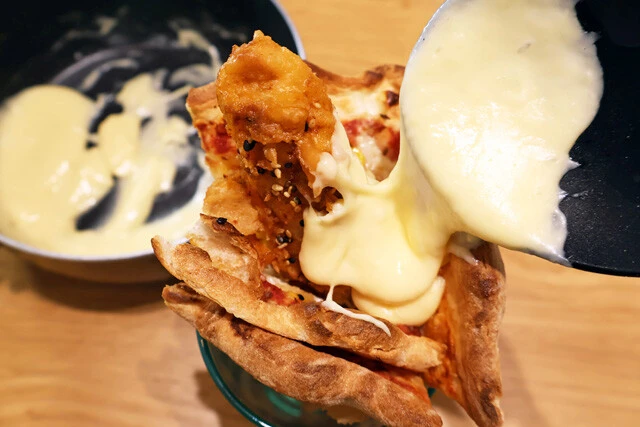 (4)チーズ! 丸めたピザの隙間に(1)で作ったチーズソースを流し込めば出来上がり。片手で持って豪快にかぶりついて食べよう。チーズソースがアツアツの場合はやけどに気をつけて!