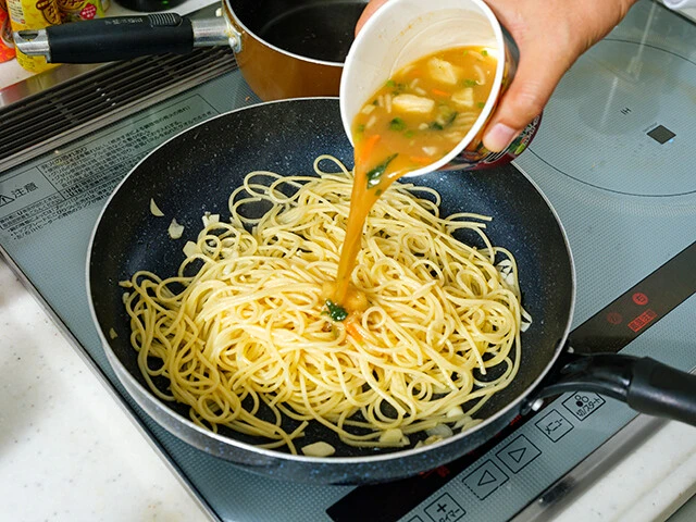 フライパンに鶏油と刻みニンニクを入れて熱し、ゆでたパスタとホウレンソウを投入してよく絡める。「吉村家 野菜畑豚骨醤油スープ」を半量入れ、水分が飛ぶまで炒めよう