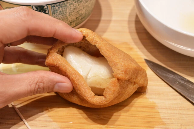 (3)包む! 最強どん兵衛 きつねうどんのお揚げを食器に移し、熱湯に浸す。柔らかくなったら取り出して側面から切り開いて(2)を包むように入れる。開いた箇所は爪楊枝などで閉じるとよい