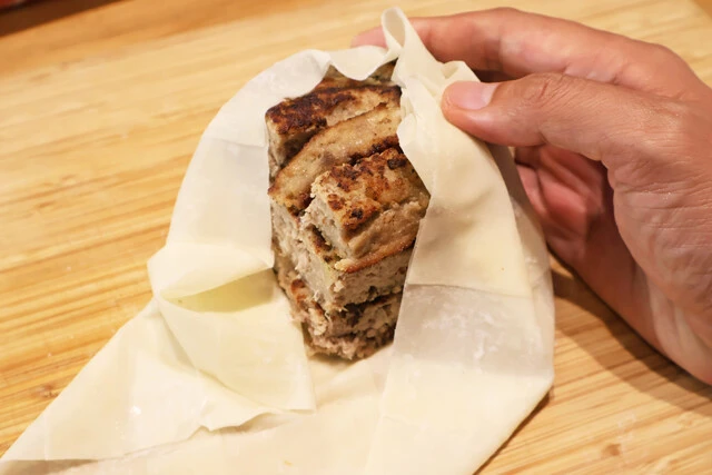 （２）包む！　びっくりドンキーのハンバーグを正方形にカットして（１）の中心部に重ね、皮で全体を包み込む。ハンバーグのサイズは小さいものでも問題ないが、ここはどデカくいこうぜ！