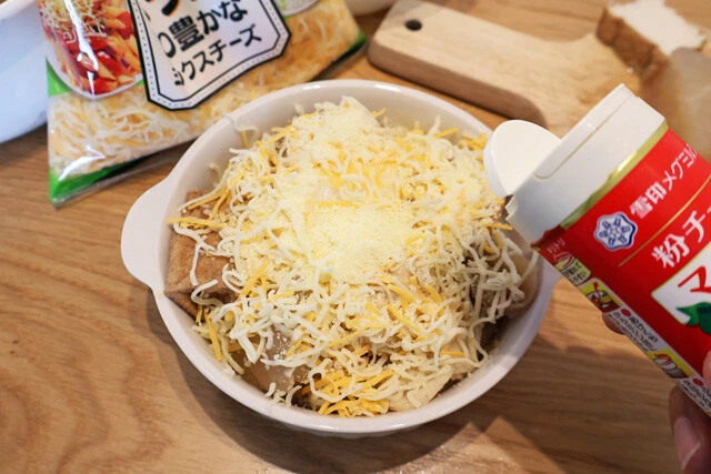 (3)チーズ! (2)の上からとろけるチーズをたっぷりとのせ、さらに粉チーズも全体にバシがけ。粉チーズはなくても問題はないが、焼き色がつきやすく見栄えがよくなる。ぜひ使おう