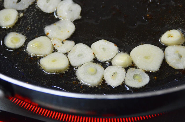 (2)ニンニク! ステーキを焼き終えたフライパンに薄切りにしたニンニクを入れ、残った油を使い弱火でじっくり揚げよう。油が少ない場合は足してOK。火が通ったら取り出し、油を切る