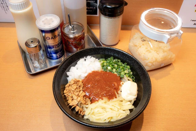 人気メニューは、チーズやマヨネーズがもともとのっている『辛まぜそば』（890円）。特製辛味噌ダレと特製スープがマッチする。また、卓上には定番のお酢やラー油のほか、ニンニク、粉チーズ、マヨネーズなども。どれも無料で混ぜ放題