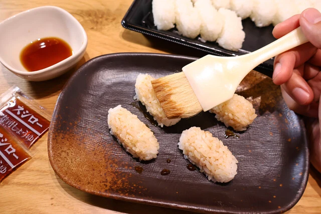 （１）塗る！　しゃり玉をテイクアウトする際に無料の醤油をいくつかもらい、皿にあけたらハケなどを使ってしゃり玉全体に塗る。基本は醤油だが、お好みで味噌やチューブ調味料も試そう