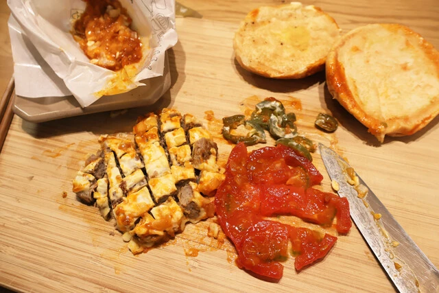 (1)カット! スパイシーモスチーズバーガーを解体し、チーズが付着したパティ、トマト、ハラペーニョを細かくカットする。トマトは刻みすぎて水っぽくならないように気をつけよう