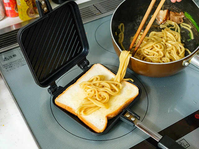 「お水がいらない...」を調理後、スープを半分に減らしてから加熱し水分を飛ばす。食パンに業務スーパーの鶏油を吸わせ、のりと麺を挟んでホットサンドメーカーで焼けば完成!
