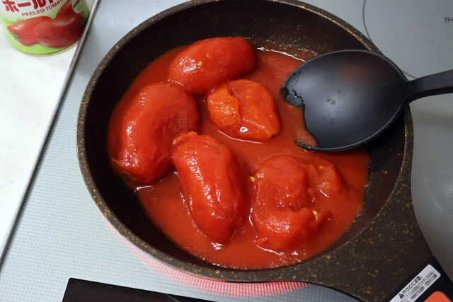 (1)トマト! ホールトマト缶をフライパンに開けて中火で加熱する。トマトを潰すようにほぐしながら焦がさないように気をつけつつ、全体が煮立ってくるまでしっかりかき混ぜよう