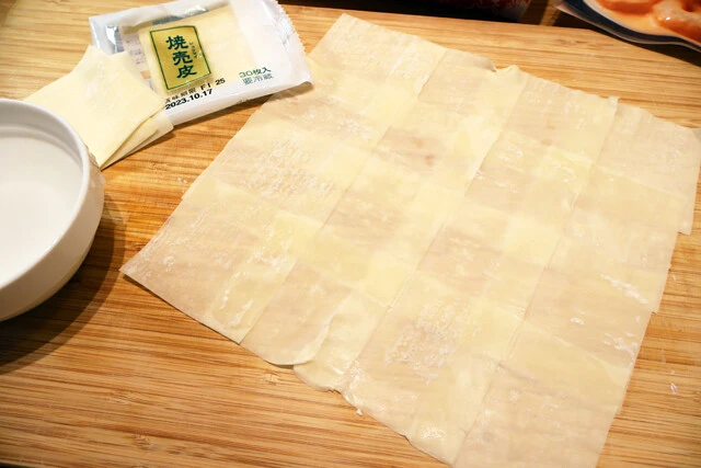 （１）つなぐ！　しゅうまいの皮の端に水をつけ、皮同士をくっつけていく。この作業を繰り返し、タテ5枚×横5枚くらいのジャンボなしゅうまいの皮を作る。皮が破れてしまわないように注意