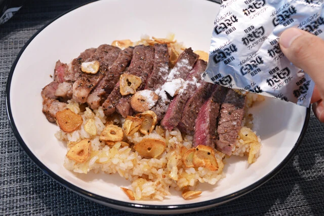 (4)パウダー! (3)を皿に盛ったら(1)と(2)を上からのせ、仕上げにわさビーフのツンピリパウダーを全量ぶっかけ! いまだかつてない猛烈な刺激が肉とガーリックライスの味を引き立ててくれる