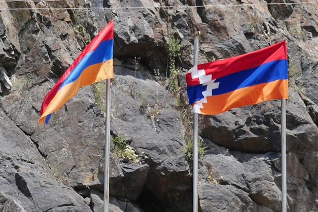 アルメニア(左)とナゴルノ・カラバフ(右)のボーダーにたなびく旗。白いギザギザはアルメニアから切り離された地域であることを示している
