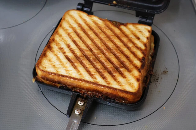 (4)焼く! あとはホットサンドメーカーを閉じ、両面を焼き上げれば完成。今回は中身を見せるため半分にカットしたが、ソースと肉汁がたっぷり閉じ込められているのでかぶりつき推奨!