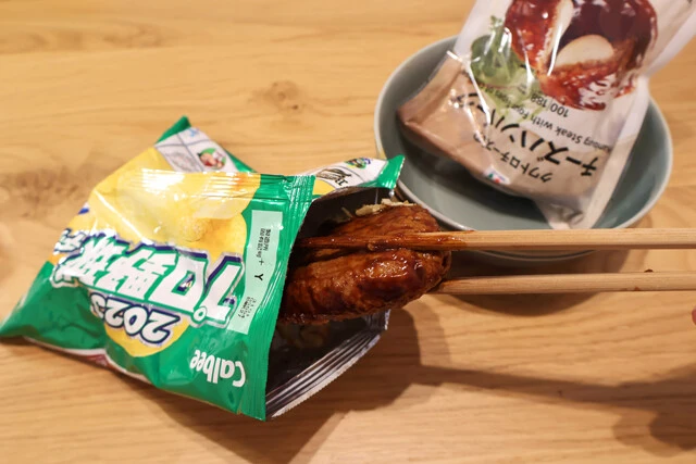 （３）シャカシャカ！　（２）を開封したらレンチンしておいたハンバーグを入れ、開け口を握ってシャカシャカと振り、ハンバーグ全体にポテトをまぶす。取り出せばポテチを衣にしたメンチカツの完成！