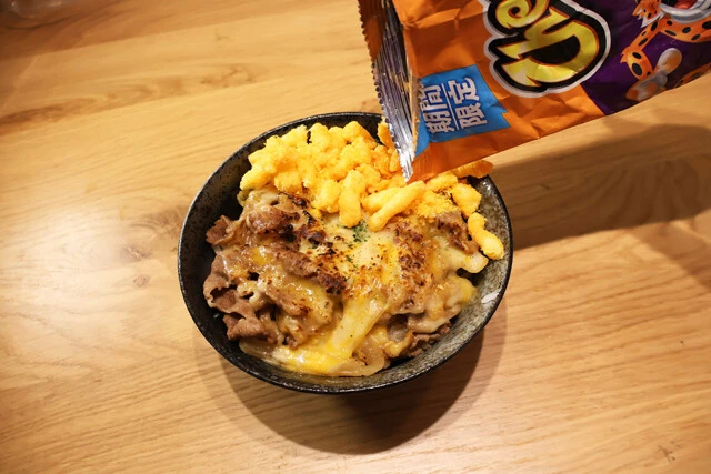 (3)砕く! チートスを袋の上から押し潰し、半量ほどをひと口サイズに砕く。潰しにくい場合は先に袋の上部を軽く開けるとよい。準備できたらチー牛に好きなだけ振りかけて食べよう