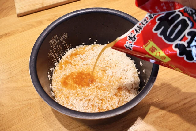 （２）スープ！　米をといで水気をよく切ったら、炊飯器に鍋スープを注ぐ。分量は水で米を炊くときと同じでOK。米2合を炊くなら、炊飯器の2合の目盛りまでスープを注ごう