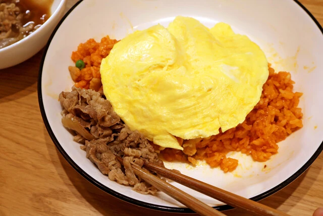 (3)盛りつけ! チキンライスの形を整えて皿の中央に山状に集め、その上から(2)をのせてオムライスにする。さらに吉野家牛丼の具を横に添えよう。ここでチーズやマヨネーズ足すのもアリ!