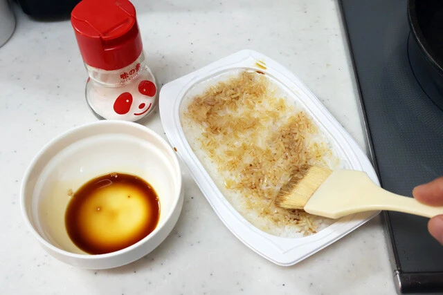 (1)塗る! レンチンご飯を温めたらフタを剥がし、ハケなどを使って表面に醤油を薄くのばして塗る。塗ったらその面を下にしてフライパンに移し、もう片面にも醤油を薄く塗ろう