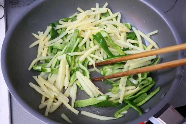 （２）炒める！　クックドゥ青椒肉絲用のレシピに従って調理を進める。細切りにしたピーマンとタケノコ水煮を油を引いたフライパンで炒め、火が通ったら皿にいったん移しておこう