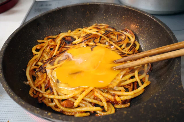 (2)つなぎ! 焦げ目がついたら溶き卵を落とし、そのまま焼いて卵を固めることで全体の一体感を出していく。その後スライスチーズものせて溶かすとより強固になり、おいしさもアップ!