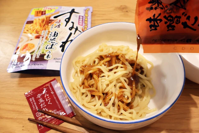 (2)まぜる! ゆでた麺を皿に移したらまぜそばのタレをかけ、全体に混ぜる。調味油や辛味ダレなど、別添調味料がある場合はこの時点で混ぜるか、仕上げでソーセージの上からかける