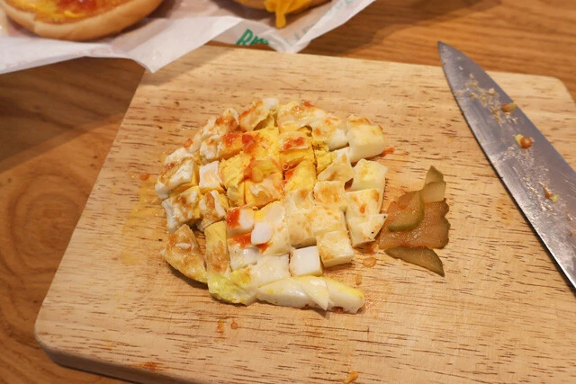(1)切る! エグチを解体し、卵、ピクルスを細かく切り刻んで深めの食器に移す。また、バンズに付着したオニオンも取って食器に移そう。余ったエグチはそのまま食べても十分ウマい