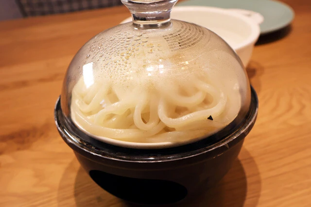 (3)燻製② うどんの水けをしっかりと切ったら燻製器に詰め込んで燻製をする。うどんが皿にこびりつきやすいため、皿に薄く油を塗ってもよい。全体にほんのり色がついたら取り出そう