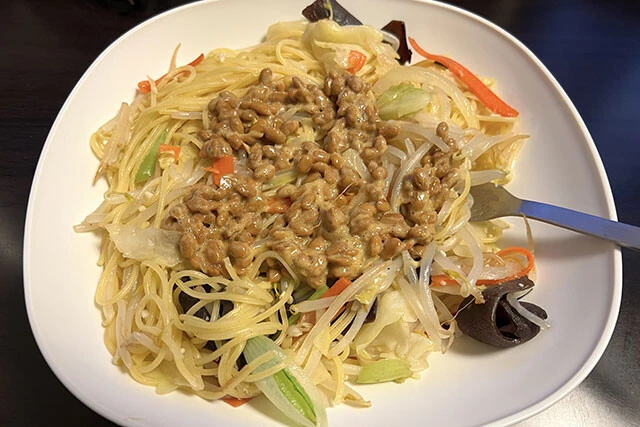 骨しゃぶり氏の鉄板レシピ。カット野菜と納豆をパスタにのせる。「ラクに作れる上、確実に96点が出るのでヘビロテしている」（同氏）