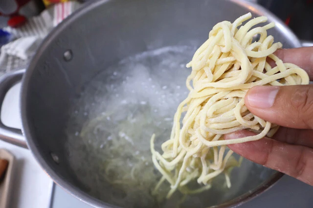 (1)ゆでる! 鍋にお湯を沸かして中華麺とソーセージをゆでよう。麺がゆで上がったらザルで湯切りする。ここでさらに熱湯をかけて、麺のぬめりを取るとよりおいしく食べられる