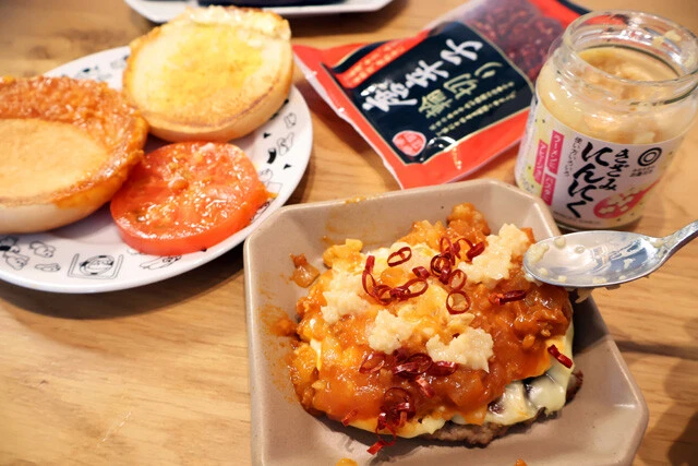 （３）味変！　モスチーズバーガーのバンズを外し、トマトソースの上に刻みにんにくと輪切り唐辛子を適量のせてアラビアータ風にアレンジ！　バンズは使わないので後で食べよう
