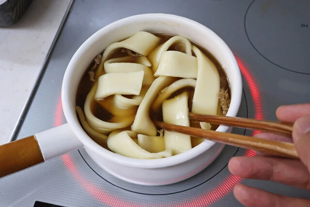 (2)煮込む! (1)がグツグツしてきたら続いてうどんを投入する。どんなうどんを使っても問題はないが、オススメは極太のゆでうどん。よく煮込んで麺に味をしっかり染み込ませよう