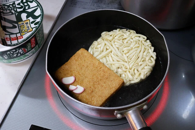 (1)ゆでる! 鍋にたっぷりのお湯を沸かし、どん兵衛きつねうどんの麺、お揚げ、かまぼこを入れて5分ほどほぐしながらゆでる。粉末スープは後で使うので入れずに残しておくこと