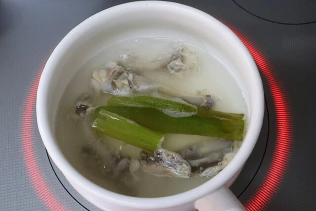 （２）だし！　軽く水洗いした骨を2分間煮込み、お湯を捨て再び骨を流水で洗う（湯引き）。その後、水と骨を鍋に入れ、中火で60分ほど煮出す。ネギの青い部分もできれば入れよう