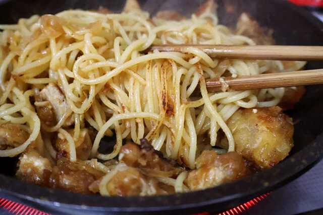 （４）焦がす！　パスタにソースが絡んで茶色くなってきたら火力を上げて麺を焦がす。トンテキは焦げないようにパスタの上に避難させておくとよい。麺の表面がカリッとしてきたら完成だ！