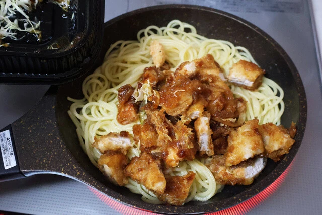 （３）炒める！　フライパンでバターを熱し、溶けたらゆで上がったパスタを投入。バターがなじんだらトンテキ、刻みニンニク少々を入れ、中火で炒める。トンテキのソースは残さず入れよう