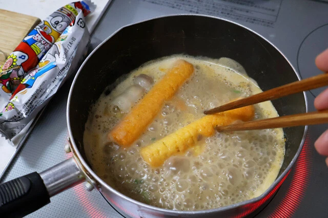 （３）煮込む！　スープのほうは火力を強めてグツグツと煮立たせ、うまい棒チーズ味を投入して溶かしていく。3本ほど入れて溶かせばかなり濃厚化するが、お好みでさらに追加してもOK！