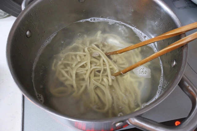 (2)ゆでる! 鍋にお湯を沸かして中華麺をゆでる。麺は極太麺推奨。ゆで終えたらザルに移して熱湯をかけ、麺のぬめりを流すとよりおいしくなる。水気を切ったらアツアツのまま丼へ