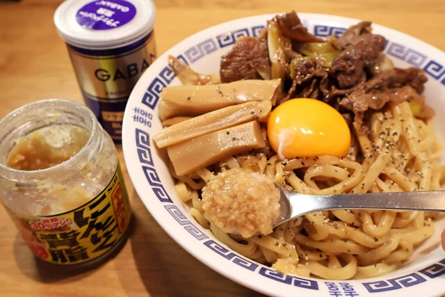 (4)仕上げ! 牛肉とネギを盛りつけたら麺の中央に軽くくぼみを作り、そこに卵黄を置く。やみつきにんにく背脂をたっぷり入れ、メンマや黒こしょうなどお好みのトッピングをすれば完成!