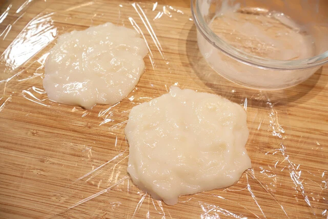 （２）成形！　ラップを広げてサラダ油を薄く塗り、（１）が触れる程度に冷めたら手にとってラップの上でバンズの形に成形していく。厚みがあるほうが見栄えはいいが、硬くなるのでほどほどに