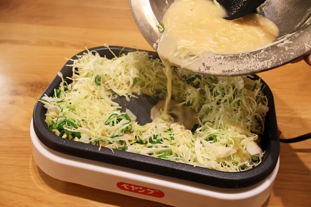 （３）焼く！　ホットプレートやフライパンを加熱したらまず具材を軽く炒めて土手を作り、中央に生地を流し込む。火が通ってきたら少しずつ混ぜ合わせ、さらにしっかり焼いていこう