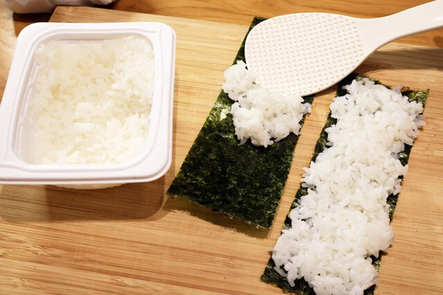 （２）ご飯！　おにぎり用の焼きのりにご飯を薄く盛る。押し潰さないように、優しく盛るのがコツ。普通のご飯を使うのが基本だが、バターライスやドライカレーを使うアレンジもウマい！