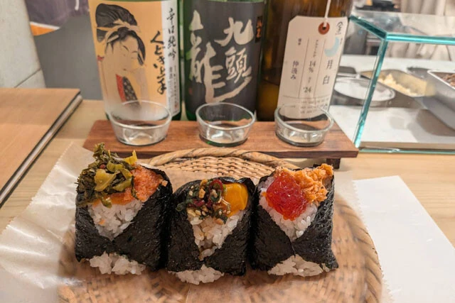 おにぎり専門店の居酒屋業態「夜山太郎」の（左から）明太子×高菜おにぎり（570円）、麻薬たまごおにぎり（570円）、すじこ×鮭おにぎり（900円）と、日本酒飲み比べ（1400円）