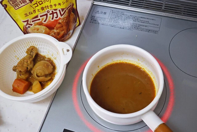 （１）加熱！　レトルトのスープカレーを鍋に開けて加熱する。温まったら具材を取り出し、スープはさらに加熱。しっかりかき混ぜながら煮立たせよう。焦げつかないように注意すること