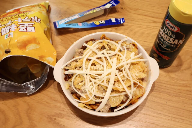（３）仕上げ！　ハンバーグをスプーンなどで潰してひき肉状にし、その上から全体を覆うように砕いた堅揚げポテチ、細くしたさけるチーズをのせる。さらに、粉チーズも振りかけよう