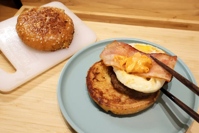 （４）重ねる！　フレンチトースト化したバンズが焼き上がったら取り除いておいた月見バーガーの中身を挟み、包み紙に戻して食べよう。シロップやバターを追加して食べるのも激ウマだ！
