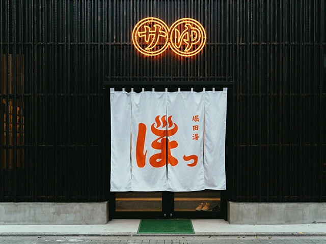 「堀田湯」の正面入り口。洗練されたモダンな黒の格子とネオンサインが特徴（写真提供／株式会社堀田湯）
