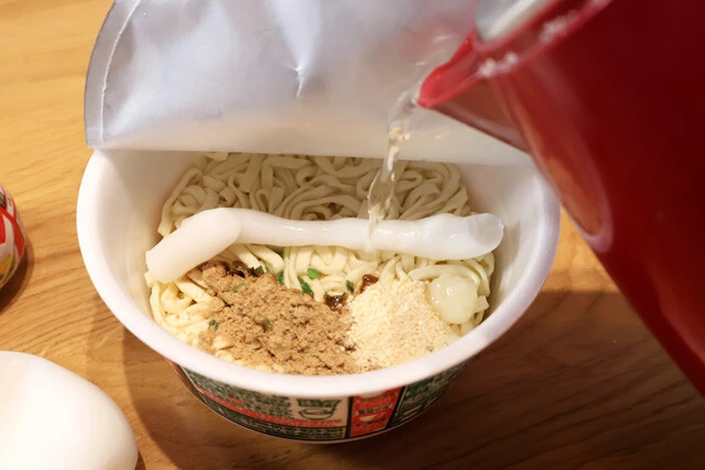 （３）熱湯！　続いて熱湯をカップ内側の線まで注ぐが、ラードの上に熱湯をかけるのがおいしく作るコツ。直接かけることでラードをしっかり溶かそう。あとはフタをして5分待つ