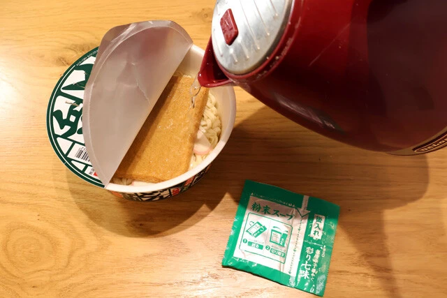 （１）熱湯！　どん兵衛特盛きつねうどんに熱湯を注ぐ。粉末スープは後で使うため、この時点では入れない。包丁などでフタに穴を開けておくと、この後の手順でザルを使わずに済む